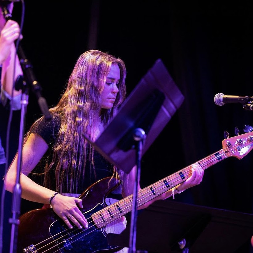 A bassist performing under violet stage lights